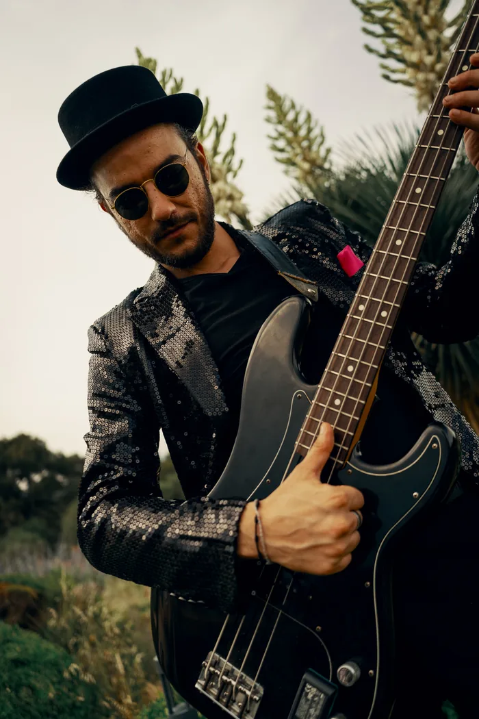 The Thrillers bass player in a black hat and sequin jacket with his bass guitar